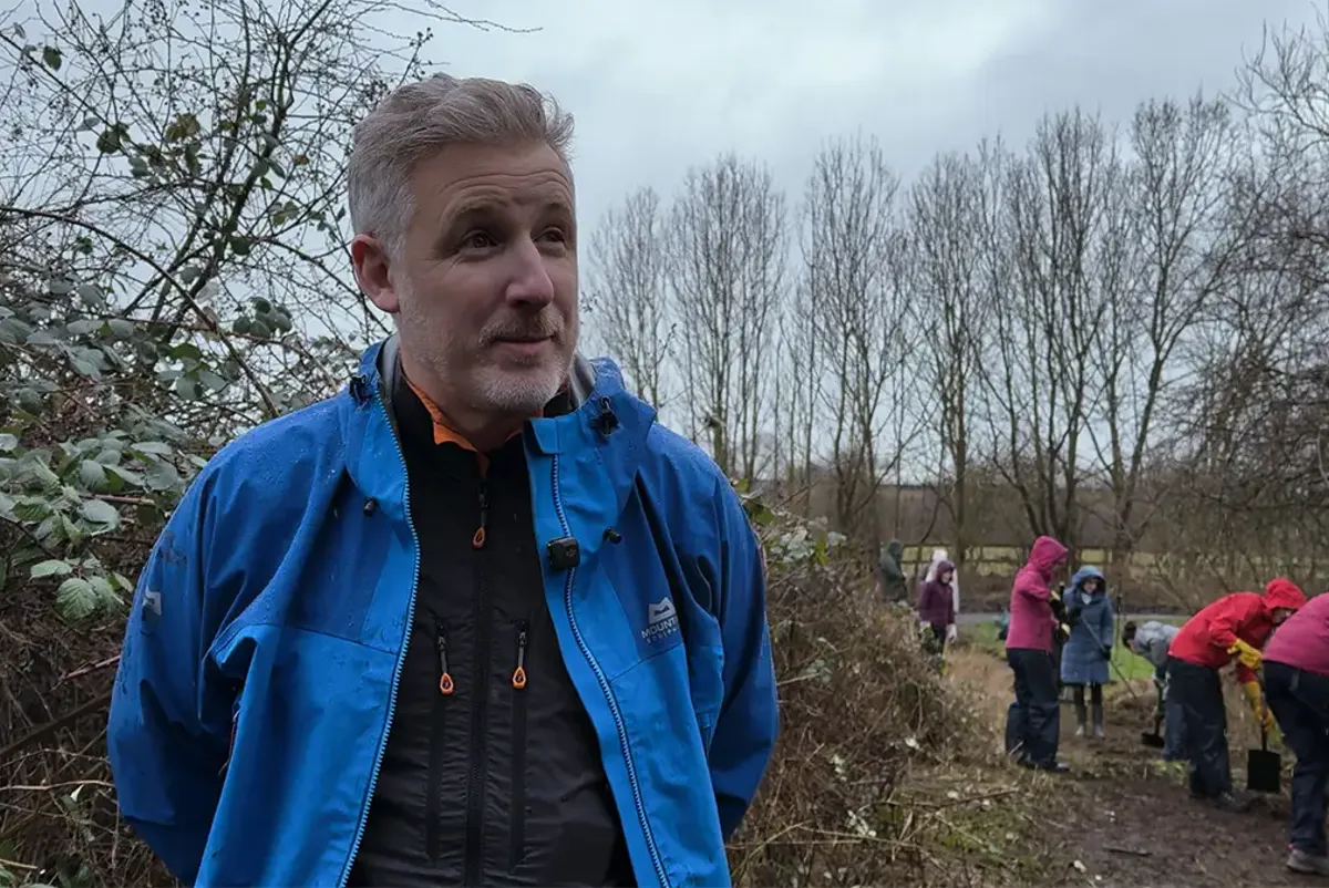 A man standing outside with people in the back.