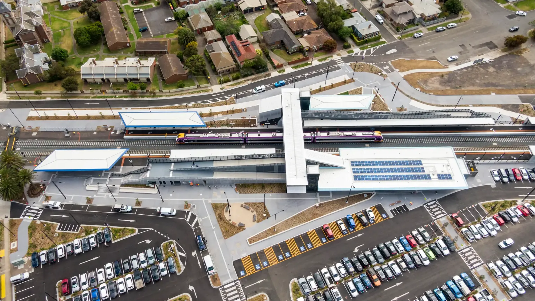 Aerial view of train station with landscaping, walkways and a car park